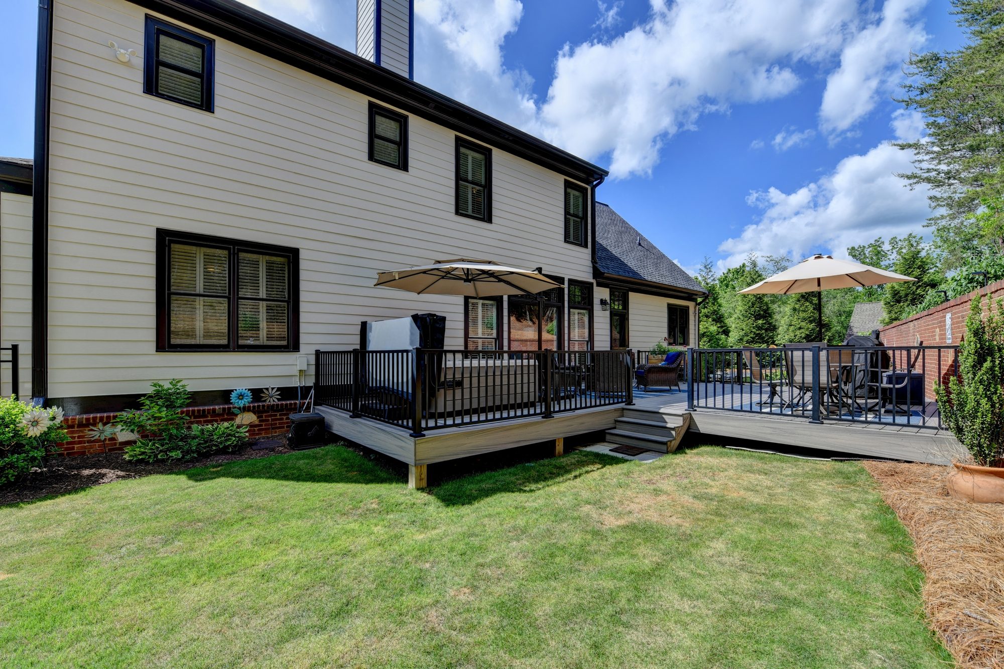 Back exterior with deck, umbrellas, and private lawn